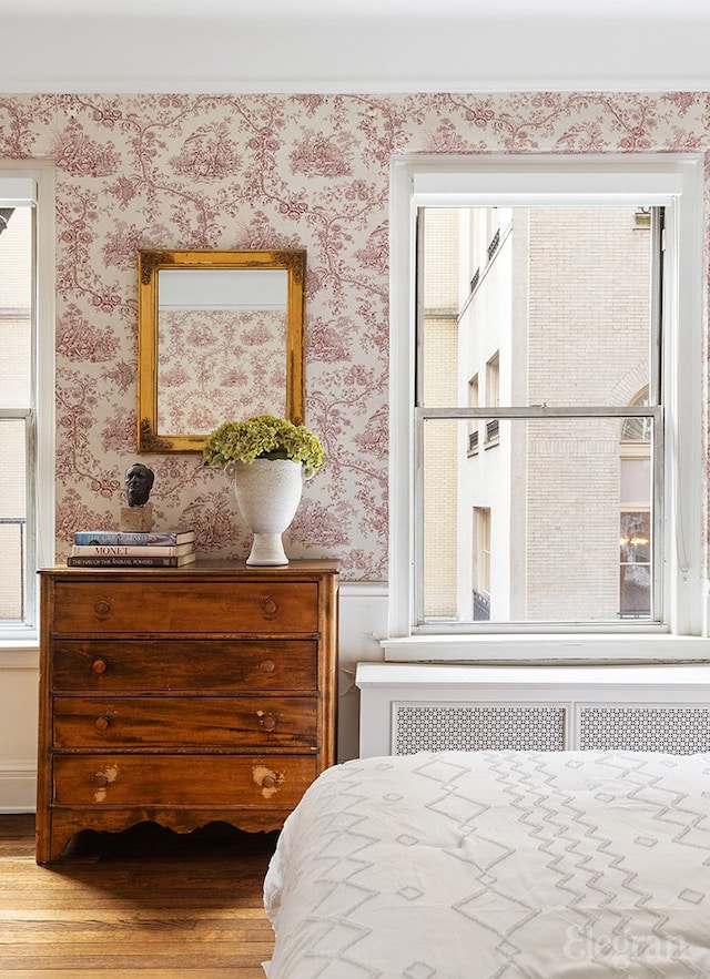 bedroom with wallpapered walls and wood finished floors