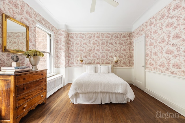 bedroom featuring radiator, wallpapered walls, wood-type flooring, and a wainscoted wall