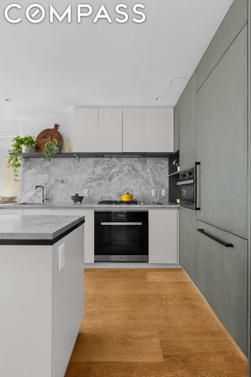 kitchen featuring tasteful backsplash, white cabinets, white gas stovetop, and black oven