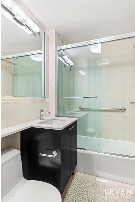 full bathroom with vanity, shower / bath combination with glass door, tile patterned floors, and toilet