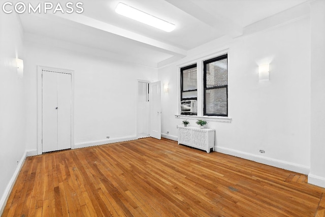 unfurnished room featuring hardwood / wood-style floors and radiator heating unit