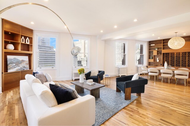 living room with radiator heating unit, light wood-type flooring, and built in shelves