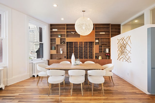 dining room with built in shelves, radiator, and light wood-style flooring