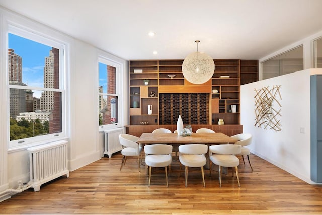 dining area featuring radiator heating unit, built in features, a healthy amount of sunlight, and light wood-type flooring