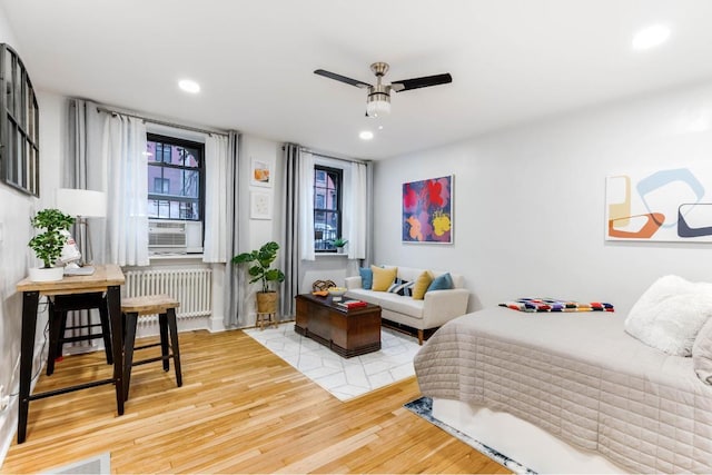 bedroom featuring ceiling fan, cooling unit, radiator heating unit, and light hardwood / wood-style floors