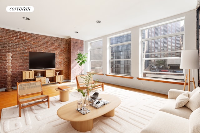 living room with brick wall, a wealth of natural light, and light wood-type flooring