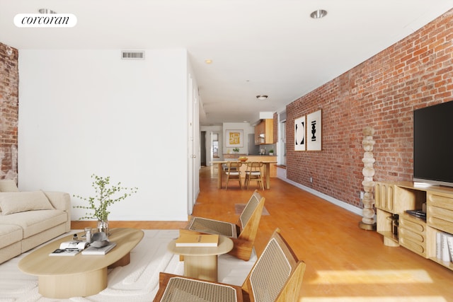 living room with light wood-type flooring and brick wall