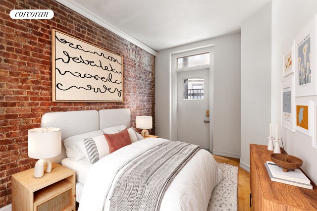 bedroom with ornamental molding, brick wall, and hardwood / wood-style floors