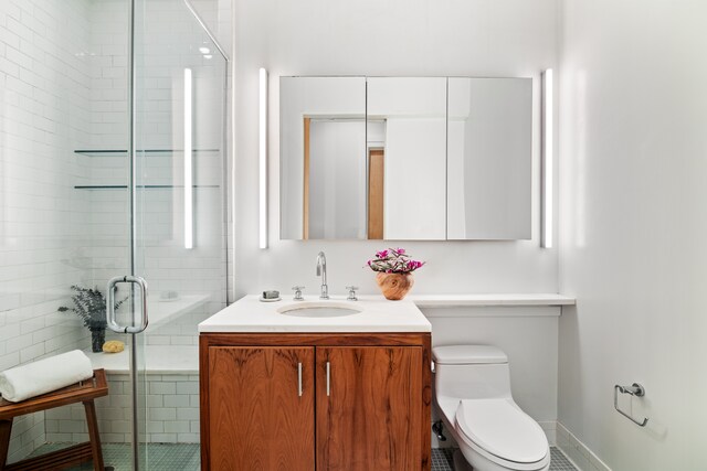 bathroom with tile patterned flooring, vanity, a shower with door, and toilet