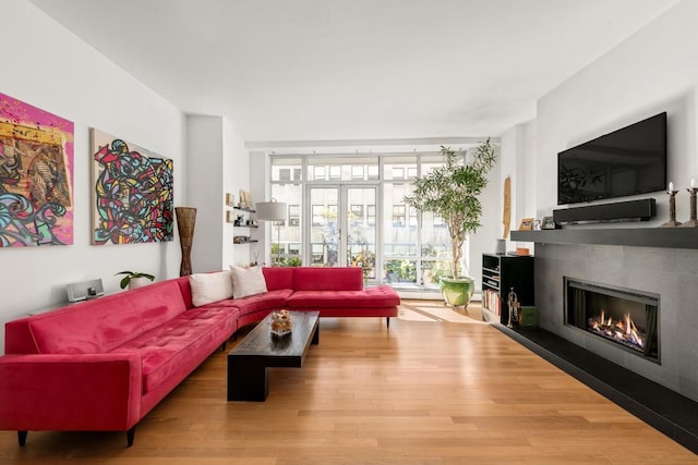 living room featuring hardwood / wood-style flooring, a tile fireplace, floor to ceiling windows, and french doors