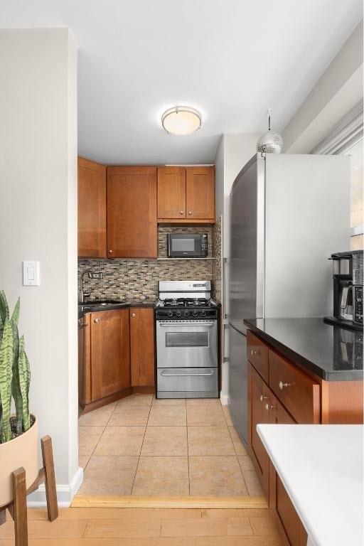 kitchen featuring appliances with stainless steel finishes, sink, light tile patterned floors, and decorative backsplash