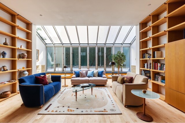 sitting room with wood finished floors, plenty of natural light, built in shelves, and expansive windows