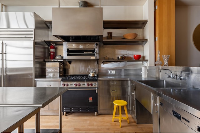 kitchen featuring a sink, stainless steel counters, open shelves, and high end appliances