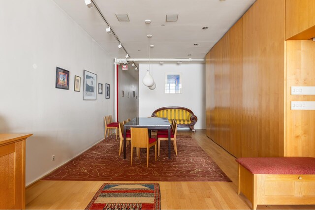 dining space featuring light wood finished floors and rail lighting