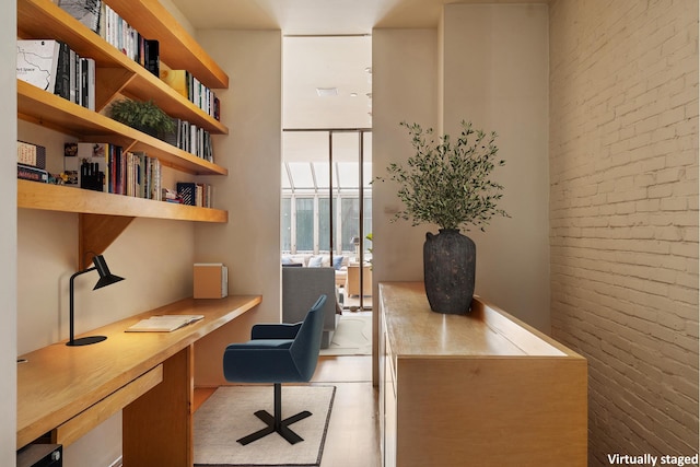 home office with floor to ceiling windows, built in desk, and brick wall