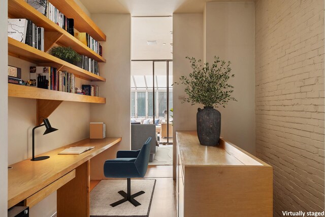 office with built in study area, brick wall, and a wall of windows