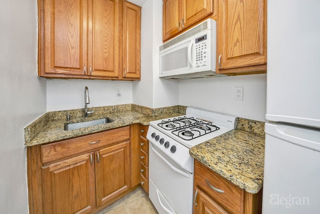 kitchen featuring light stone counters, sink, white appliances, and light tile patterned flooring