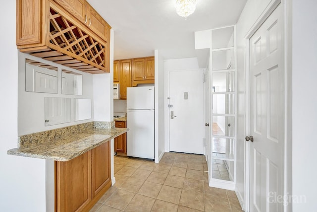 kitchen featuring light stone countertops, white fridge, and light tile patterned floors