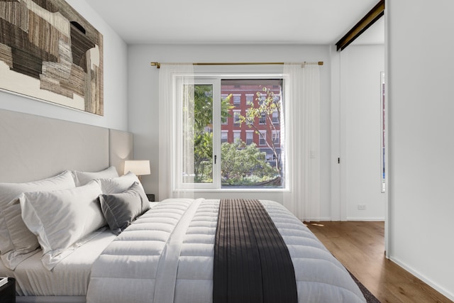 bedroom with multiple windows and hardwood / wood-style floors