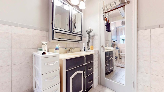 bathroom featuring tile walls, vanity, tile patterned flooring, and toilet