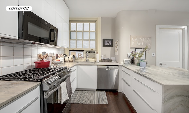 kitchen featuring dark wood finished floors, decorative backsplash, appliances with stainless steel finishes, white cabinetry, and a peninsula