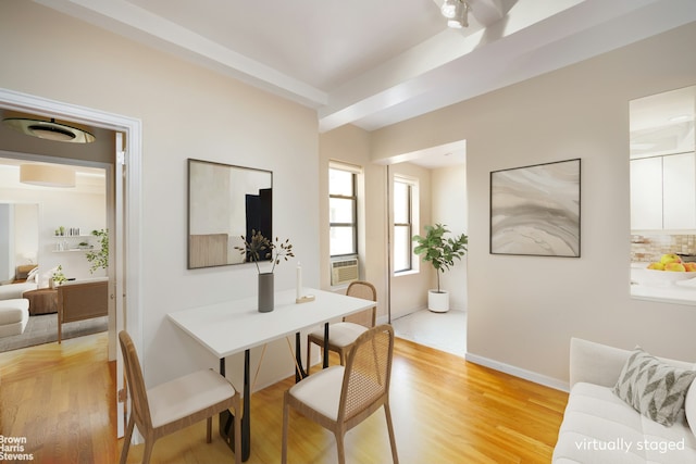 dining area with baseboards, beam ceiling, and light wood finished floors