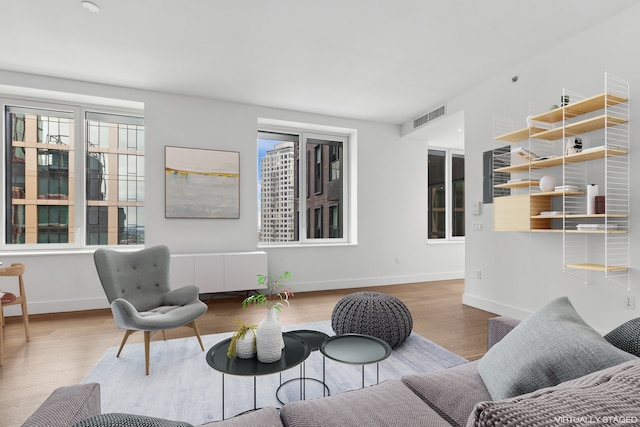 living room featuring baseboards, visible vents, and wood finished floors