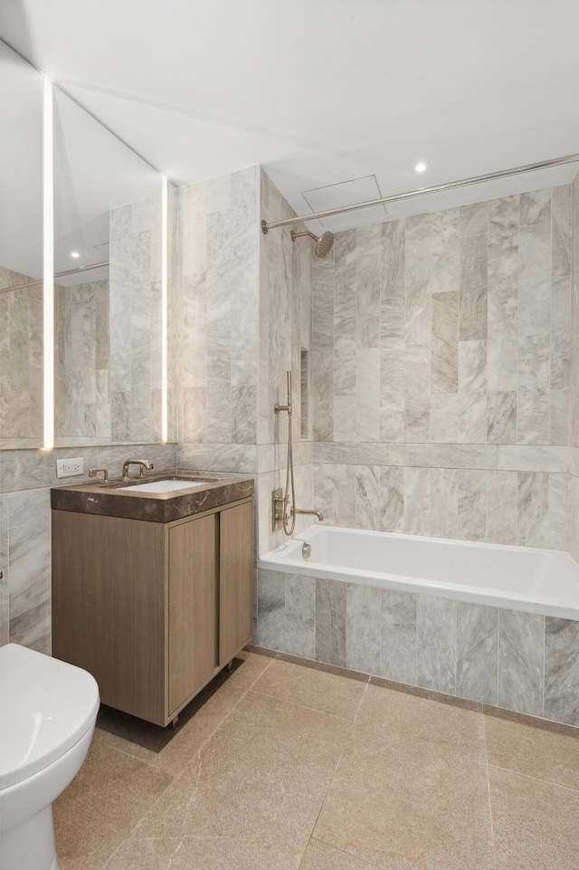 full bath with vanity, toilet, tiled shower / bath combo, and tile walls