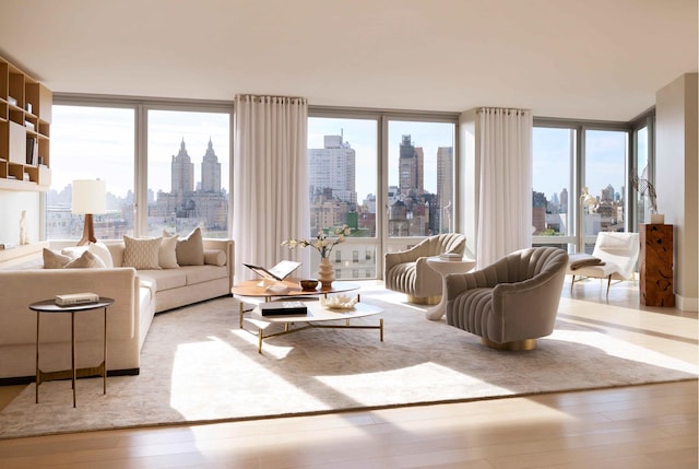 living room with a city view, wood finished floors, floor to ceiling windows, and a healthy amount of sunlight