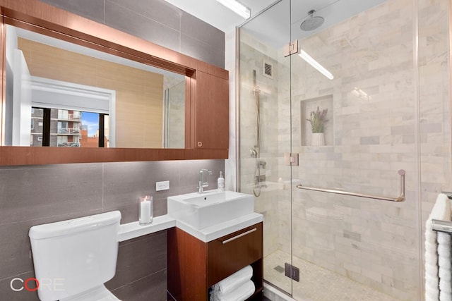 bathroom featuring a shower with door, vanity, tile walls, and decorative backsplash