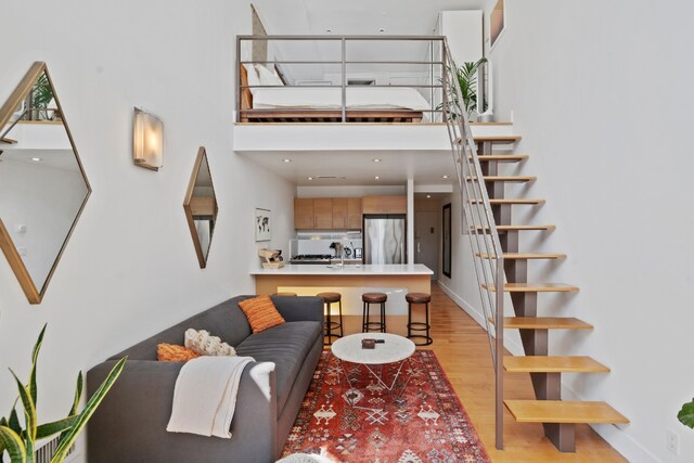 living room with sink, light hardwood / wood-style flooring, and a high ceiling