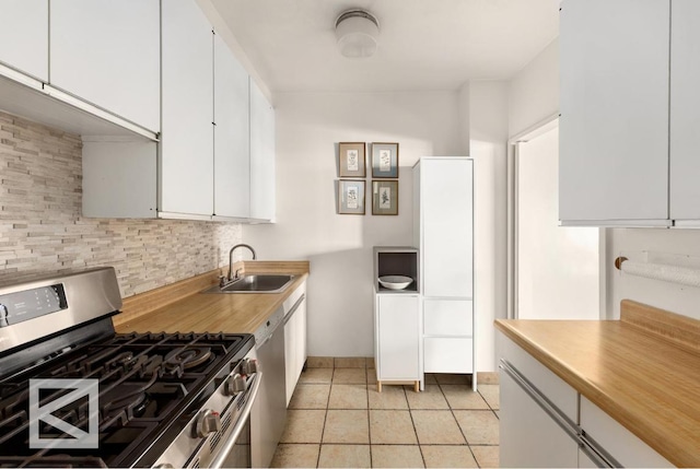 kitchen featuring sink, light tile patterned floors, appliances with stainless steel finishes, tasteful backsplash, and white cabinets