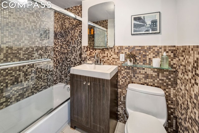 full bathroom featuring shower / bath combination with glass door, tile walls, vanity, tile patterned floors, and toilet