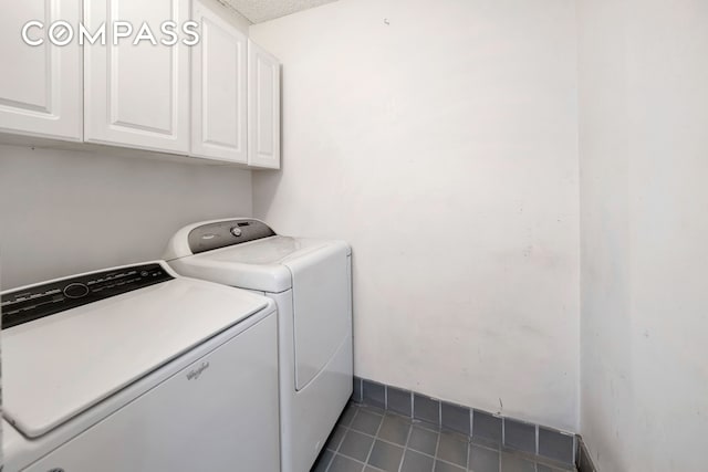 clothes washing area featuring cabinet space, dark tile patterned flooring, and washer and clothes dryer