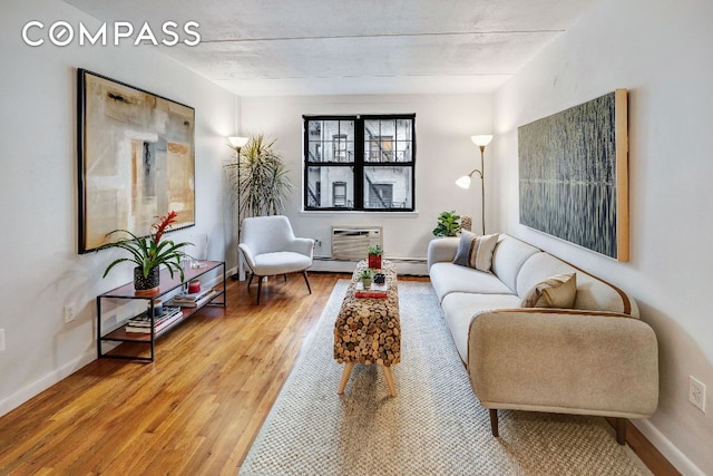 living room with a baseboard radiator, baseboards, wood finished floors, and a wall mounted air conditioner