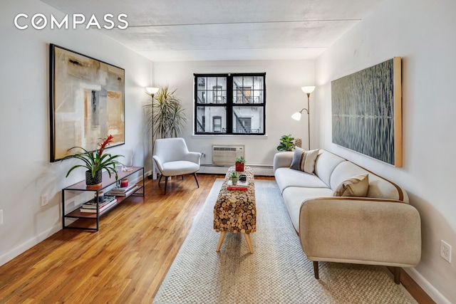 living room with baseboards, baseboard heating, wood finished floors, and an AC wall unit