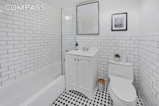 bathroom featuring vanity, bathing tub / shower combination, tile patterned flooring, toilet, and tile walls