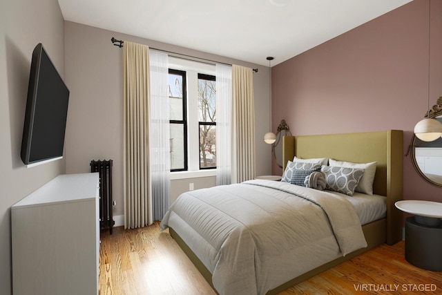 bedroom featuring radiator heating unit and light wood-type flooring