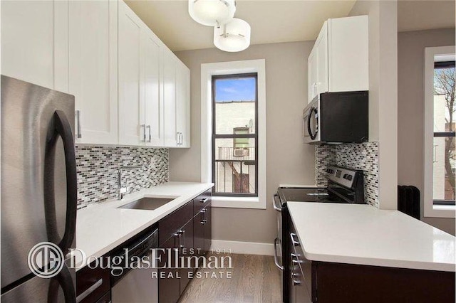 kitchen with white cabinets, dark brown cabinets, stainless steel appliances, and light countertops