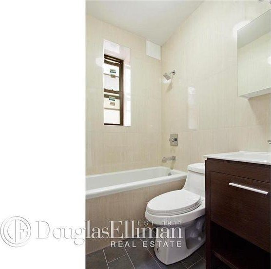 bathroom with tile walls, shower / bath combination, toilet, vanity, and tile patterned flooring