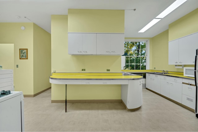 1 Sutton Pl S Unit 4C, New York City, NY 10022 - kitchen featuring white appliances, white cabinets, baseboards, and a breakfast bar area