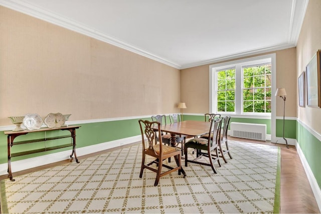 dining space with ornamental molding, radiator heating unit, and light parquet flooring