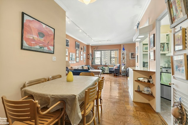 dining room with crown molding, light parquet flooring, and rail lighting