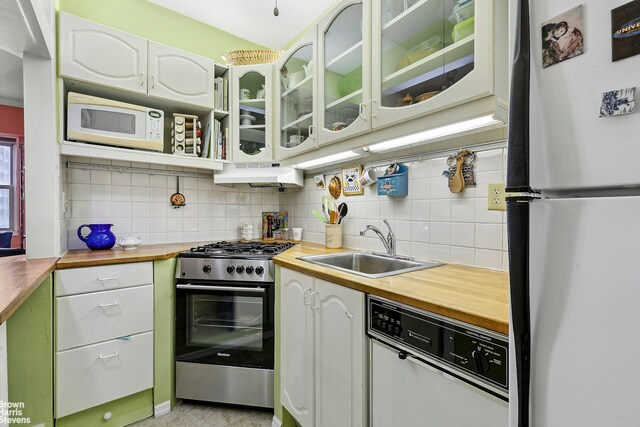 kitchen featuring butcher block countertops, white appliances, a sink, and under cabinet range hood