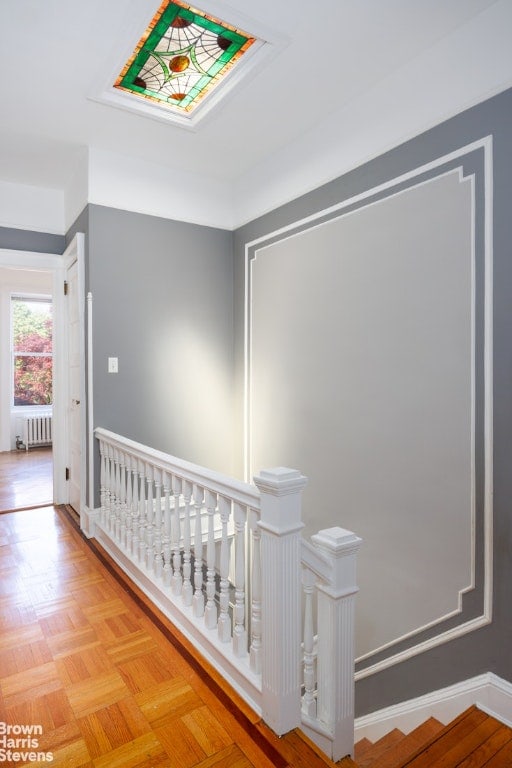 hallway featuring radiator heating unit and light parquet floors