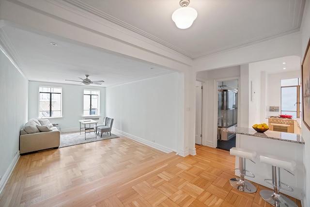 unfurnished living room with ceiling fan, ornamental molding, and baseboards