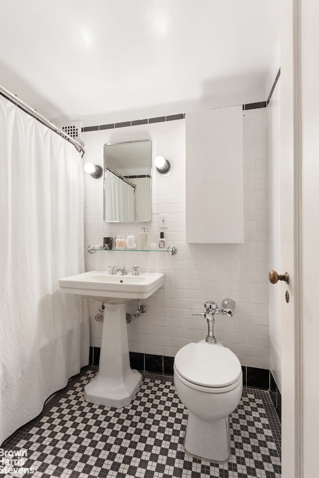 bathroom with toilet, curtained shower, and tile walls