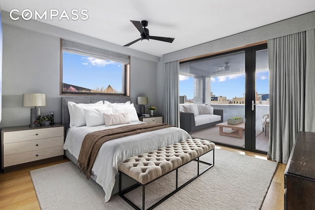 bedroom with a view of city, light wood-type flooring, a ceiling fan, and access to exterior