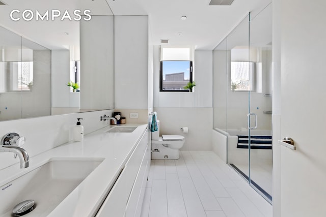 full bathroom featuring visible vents, a shower with shower door, a sink, and toilet