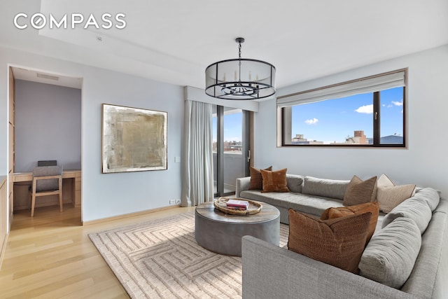 living area with wood finished floors, visible vents, baseboards, and an inviting chandelier